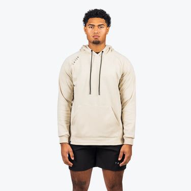 The uploaded image shows a model wearing a cream-colored professional baseball training hoodie with long sleeves, paired with black shorts, both adorned with the "TATER" logo. The hoodie, which is suitable for both sports training and casual wear, features a drawstring hood and a central front pocket. The style is modern and understated, emphasizing a practical and athletic lifestyle.