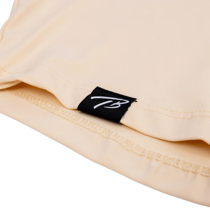 Detail of a tan short-sleeve baseball lifestyle hoodie featuring the Tater Baseball 'TB' logo on a black fabric tag, showcasing the brand's signature style.