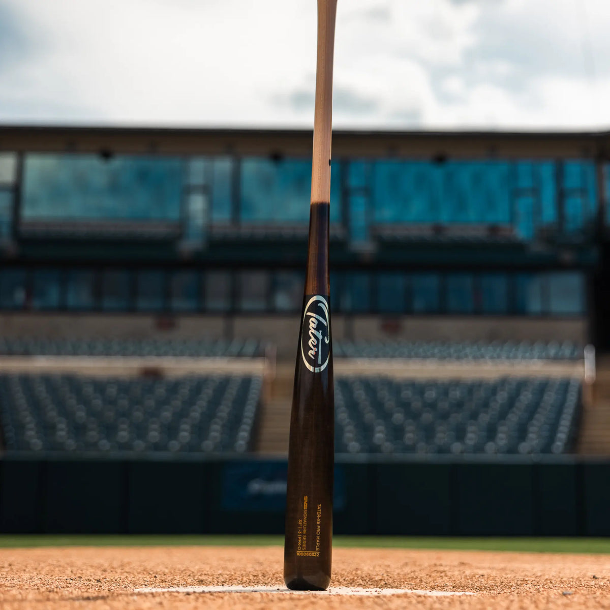 Tater Baseball&#39;s top-rated maple wood bat for hitters, standing at home plate in an empty baseball field, a preferred choice for players seeking alternatives to Louisville Slugger.