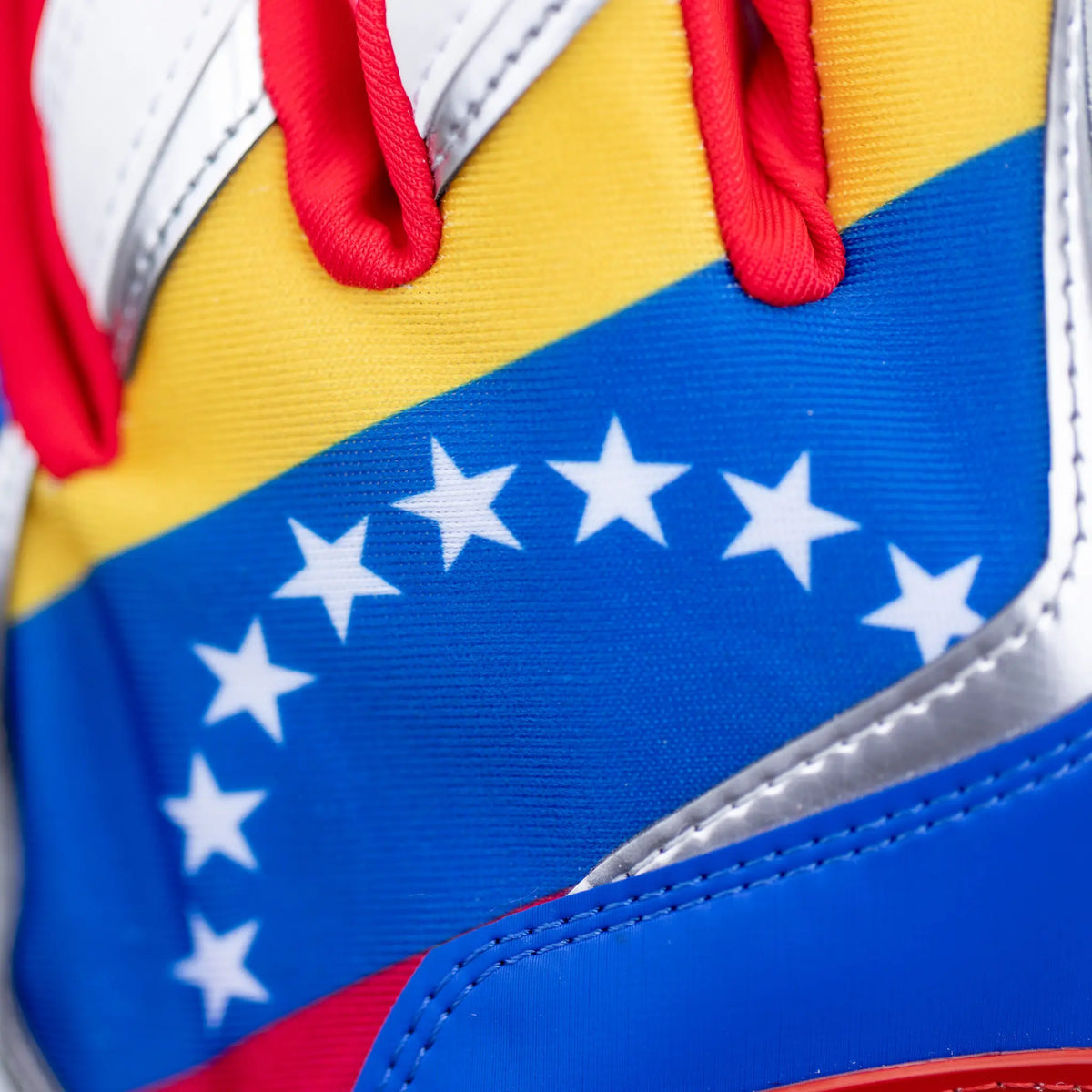 Detail of Tater Baseball batting gloves showing a close-up of the vibrant Venezuelan flag design with a starry blue band and contrasting yellow and red, symbolizing national pride on high-performance gear.
